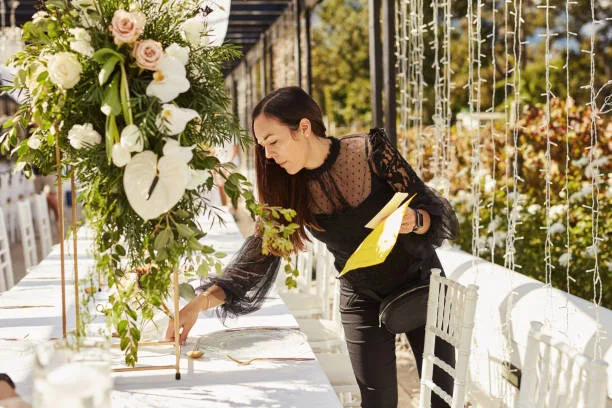 An event professional carefully styling a floral table setting